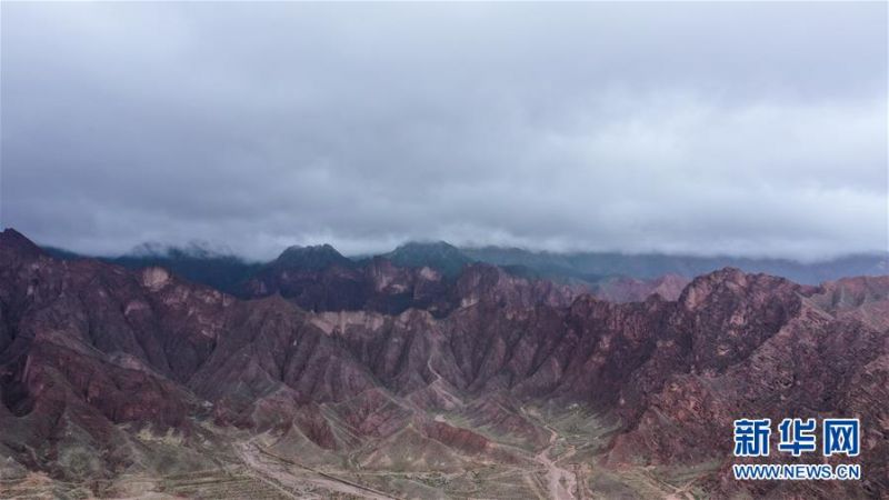 这是6月16日拍摄的位于贵德县尕让乡松巴村附近的丹霞地貌(无人机照片)。 夏日时节,位于青海省海南藏族自治州的贵德县迎来连日降雨,多彩的丹霞地貌在雨后色泽愈发鲜艳,在云雾的笼罩下形成一幅幅独特画卷。 新华社记者 吴刚 摄