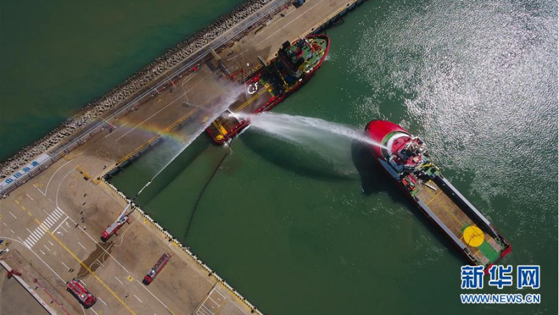 6月12日,在海口港马村港区危险品船舶船岸应急联合演习现场,工作船和消防车赶到现场后实施灭火救援(无人机照片)。 当日,海口海事局在海口港马村港区组织开展危险品船舶船岸应急联合演练。本次演练通过模拟设置一艘危险品船舶在码头作业过程中发生泄漏事故导致海域污染、船舶起火、人员受伤的场景,演练危险品码头及相关单位部门的应急处置与协作反应,提升危险品码头应急处置能力。 新华社记者 杨冠宇 摄