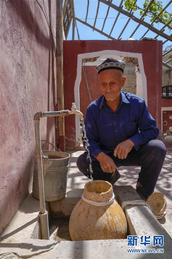 在新疆和田地区和田县布扎克村,68岁的艾比布拉·托合提在用葫芦接水(5月21日摄)。葫芦是南疆乡村常见的取水容器。 新华社记者 赵戈 摄