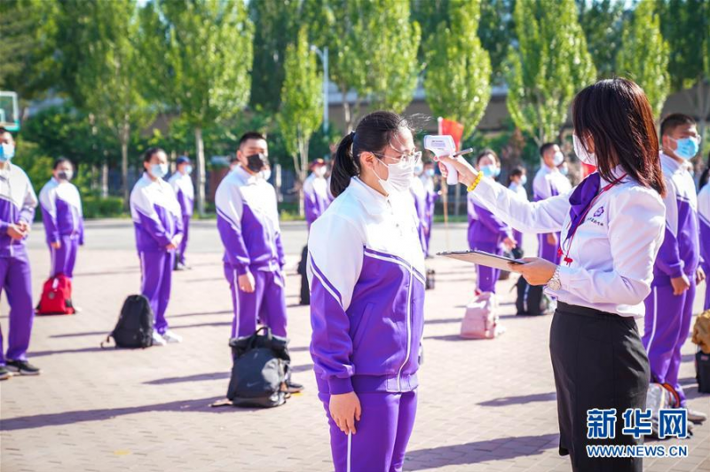 5月28日，哈尔滨市实验学校教职人员（右）为毕业年级学生测温。 当日，黑龙江省初中毕业年级返校复课，有序恢复在校学习生活。 新华社记者王松摄