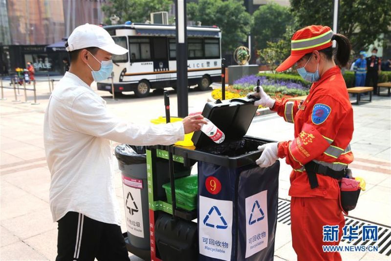 　　5月29日，在北京王府井步行街，一名行人向移动垃圾分类保洁车中投放垃圾。新华社发（郭俊锋 摄）