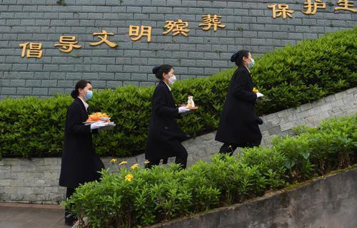 工作人員端著祭掃需要的鮮花、祈福帶、祈福燈等物代客祭掃。1