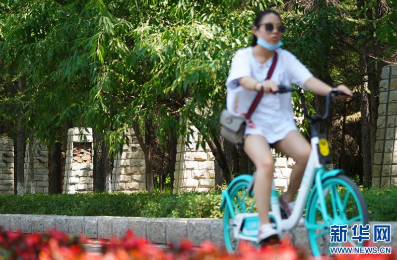 6月17日，市民骑自行车经过长春市南湖公园正在拆除护栏的围墙旁。新华社发（颜麟蕴摄）