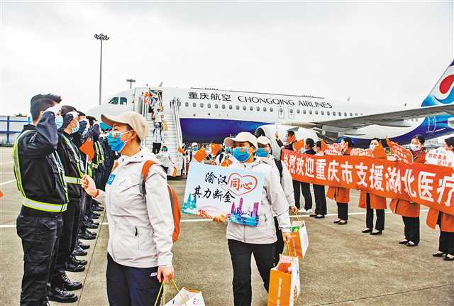 3月29日，重慶江北國(guó)際機(jī)場(chǎng)，重慶支援湖北醫(yī)療隊(duì)隊(duì)員揮舞國(guó)旗依次走下飛機(jī)。記者 龍帆 攝