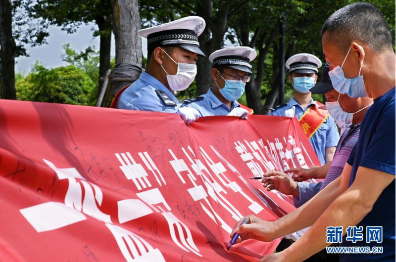 6月9日，市民在“一盔一带”守护生命横幅上签名。新华社记者 李紫恒摄