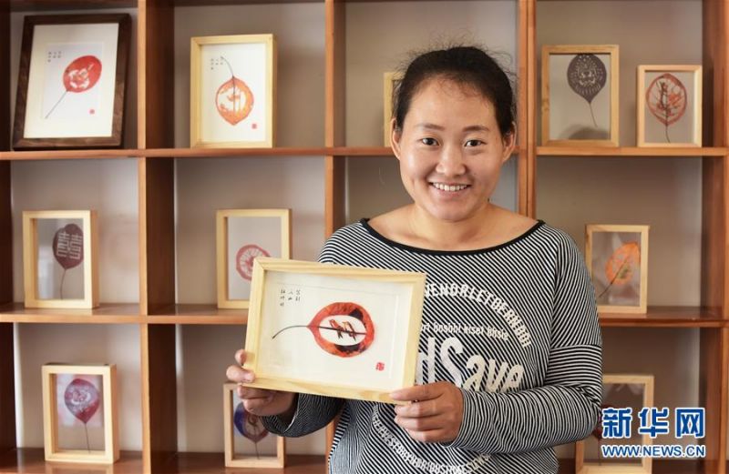 　重庆市巫山县双龙镇安静村村民刘忠梅在红叶艺术品加工工坊内展示红叶产品（5月26日摄）。新华社记者 王全超 摄
