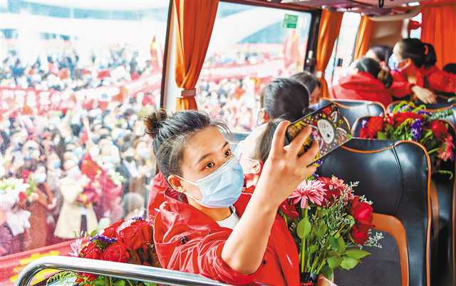 3月23日，重庆医疗队员乘坐大巴离开孝感时，一名队员在车上与前来相送的市民自拍“合影”。新华社记者 胡虎虎 摄