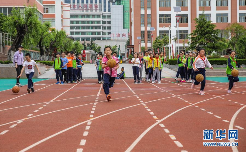 6月2日，在山东省荣成市第二实验小学的操场上，小学生们在比赛运球。 伴随着学生们的返校复课，各地中小学幼儿园的操场又热闹起来。学校在做好防控措施的同时，保证学生们的体育锻炼时间，引导学生恢复体能、放松心情。 新华社发（李信君 摄）