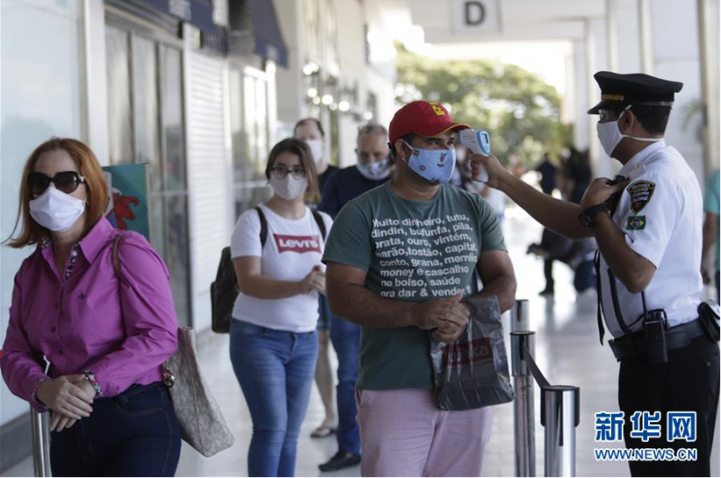 5月27日，在巴西首都巴西利亚，顾客在恢复营业的商场外检测体温。 据巴西卫生部新冠疫情最新统计数据，截至当地时间27日19时，巴西24小时内新增确诊病例20599例，累计确诊411821例。 新华社发（卢西奥·塔沃拉摄）