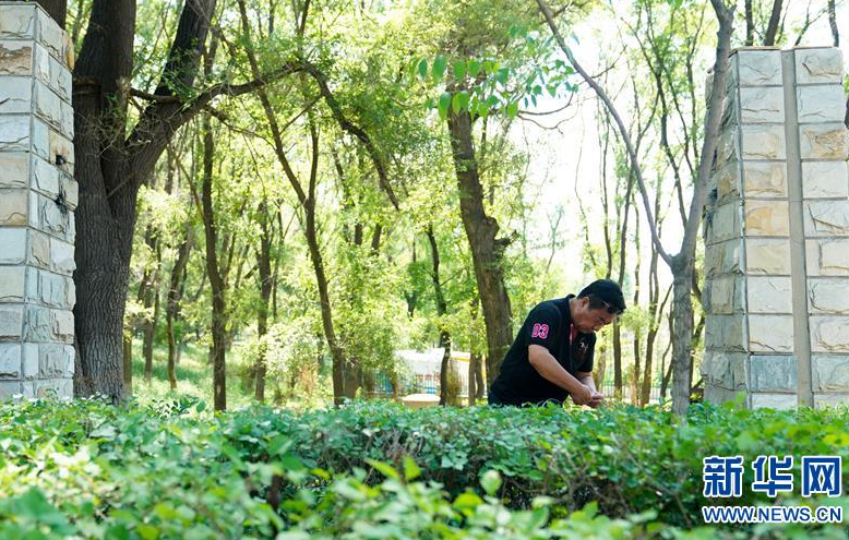 6月17日，市民在长春市南湖公园已拆除护栏的围墙旁整理背包。新华社发（颜麟蕴摄）