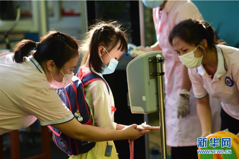 5月25日，海南省琼海市中兴幼儿园的老师在校门前为小朋友洗手消毒。 当日，海南省琼海市幼儿园大班和特殊教育学校开园。 新华社发（蒙钟德 摄）