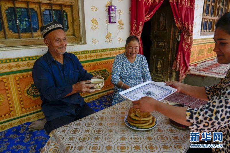 在新疆和田地区和田县布扎克村,68岁的艾比布拉·托合提(左)与家人一起休息喝茶(5月21日摄)。 新华社记者 赵戈 摄