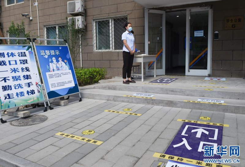 5月27日，在北京化工大学，学校工作人员在学生宿舍门口值守。 当日，北京化工大学举行学生返校复课疫情防控演练，为学生返校复课做准备。据介绍，从6月6日起，具备校园疫情防控条件的北京高校，可安排毕业年级学生自愿返校。 新华社记者 鞠焕宗 摄
