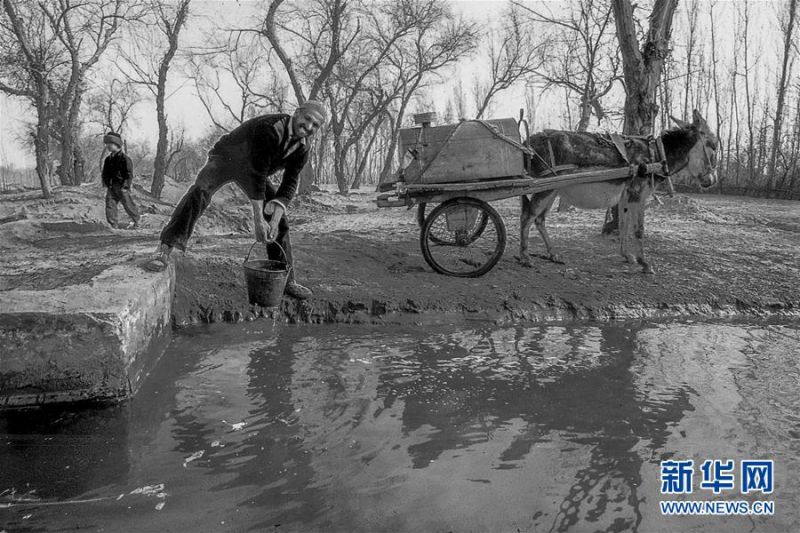 上个世纪90年代,新疆和田地区策勒县一位农民在一处涝坝边取水(资料照片)。 新华社记者 沈桥 摄