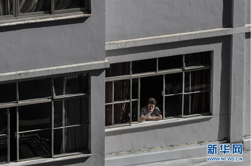 5月27日，在巴西圣保罗，一名女子从家中向外眺望。 据巴西卫生部新冠疫情最新统计数据，截至当地时间27日19时，巴西24小时内新增确诊病例20599例，累计确诊411821例。 新华社发（拉赫尔·帕特拉索摄）