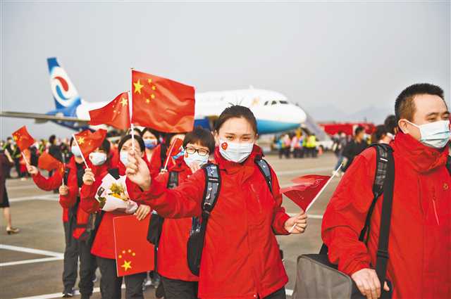 3月23日下午5时许，在重庆江北国际机场，医疗队员挥舞着国旗依次走下飞机。记者 苏思 摄