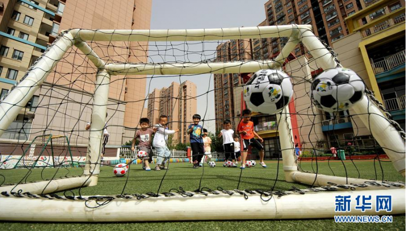 6月2日，山东省枣庄市鑫昌路小学幼儿园的小朋友在园内踢足球。 伴随着学生们的返校复课，各地中小学幼儿园的操场又热闹起来。学校在做好防控措施的同时，保证学生们的体育锻炼时间，引导学生恢复体能、放松心情。 新华社发（孙中喆 摄）