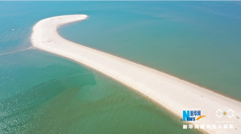 雪白的沙岸伸向大海深处，把大海分成内外两边（无人机拍摄）。新华网 王雄 摄 飞手 林楷煜