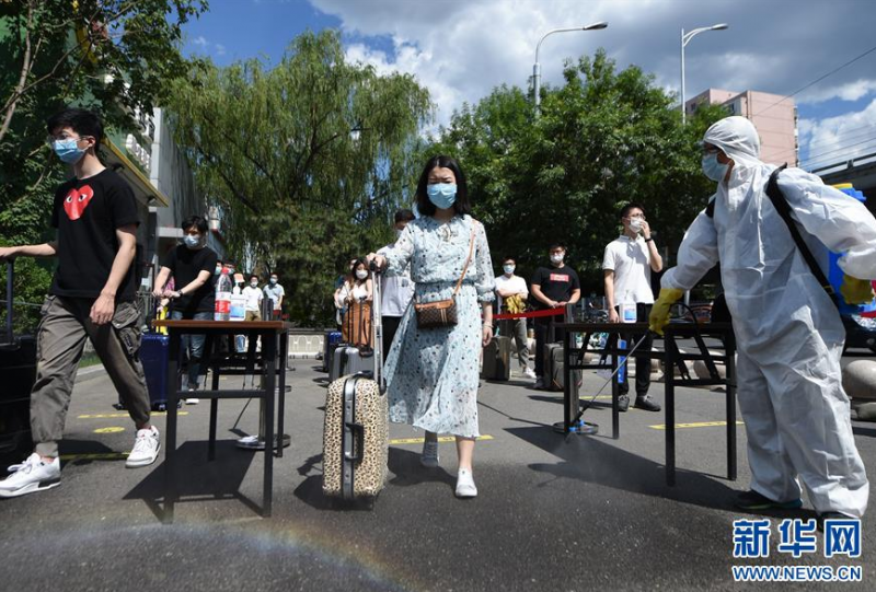 5月27日，在北京化工大学门外，学校工作人员对“返校学生”进行鞋底和行李消毒。 当日，北京化工大学举行学生返校复课疫情防控演练，为学生返校复课做准备。据介绍，从6月6日起，具备校园疫情防控条件的北京高校，可安排毕业年级学生自愿返校。 新华社记者 鞠焕宗 摄
