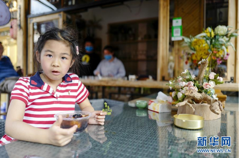 5月2日，一个小女孩在猎神村居民点的露天饮品店内品尝。新华社记者 刘潺 摄