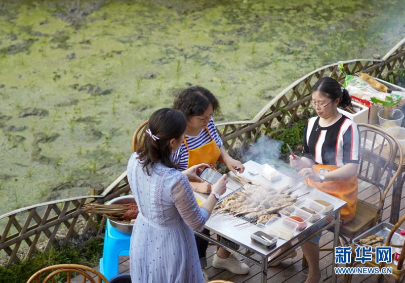 5月2日，在猎神村的一家特色民宿猎神居的院坝上，游客一边欣赏田园风光，一边品尝美食。新华社记者 刘潺 摄