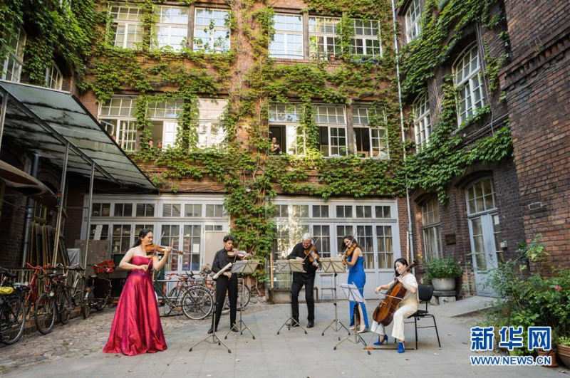 6月23日，在德国首都柏林的一处居民区，柏林国家歌剧院管弦乐团成员在“庭院音乐会”上表演。 由于新冠疫情期间暂时不能举办室内音乐会，柏林国家歌剧院管弦乐团成员选择前往社区，在社区庭院中为观众举办露天“庭院音乐会”。 新华社发（彼得·阿达米克 摄）