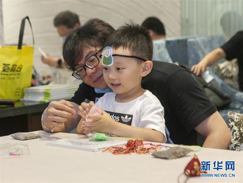 　　6月25日，在上海新世界大丸百货，父亲和孩子在端午民俗小课堂上互动。 当日是端午节，人们外出游玩，乐享假期。 新华社记者 王翔 摄