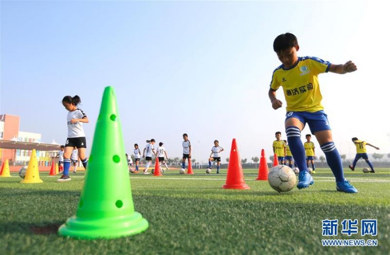7月16日，青岛通济实验学校的小球员在进行运球训练。 暑假期间，位于山东青岛即墨区的青岛通济实验学校举办暑期足球训练营，小学生在绿茵场上学习足球基础技能，享受快乐暑假。 新华社发（梁孝鹏 摄）