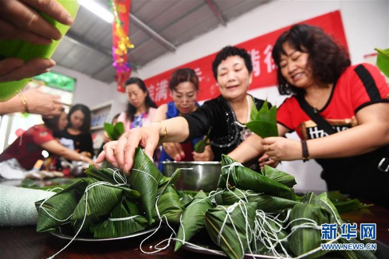 6月24日，贵阳市南明区遵义街道办事处体育路居委会“粽满飘香，情满街道”端午主题活动中，辖区群众在一起包粽子。 端午佳节将至，各地群众举行了多种多样的活动迎接这一传统节日。 新华社发（赵松 摄）