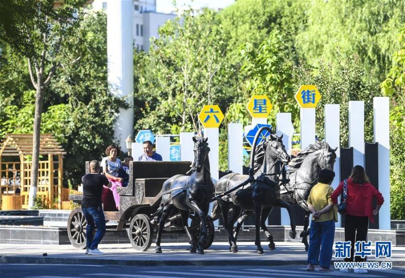 7月5日，游客在六星街的马车雕塑前观光拍照。 新华社记者 王菲 摄