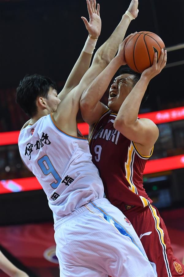 7月10日，山西汾酒股份队球员闫鹏飞（右）在比赛中突破新疆伊力特队球员周琦的防守上篮。 当日，在山东青岛举行的2019-2020赛季中国男子篮球职业联赛（CBA）复赛第二阶段（红岛赛区）比赛中，新疆伊力特队以104比71战胜山西汾酒股份队。 新华社记者朱峥摄