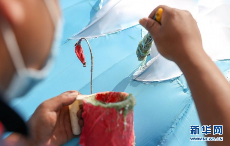 6月27日，江成财在长春市长影世纪城内修补破损的彩灯。新华社发（颜麟蕴摄）