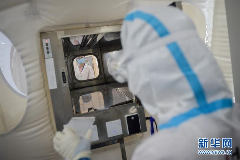 7月1日，在提取实验室内，实验人员（右）通过传递通道将物品转移到扩增实验室。 新华社记者 彭子洋 摄