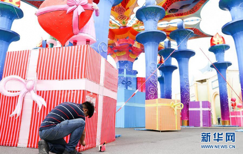 6月27日，江成财在长春市长影世纪城内修补破损的彩灯。新华社发（颜麟蕴摄）