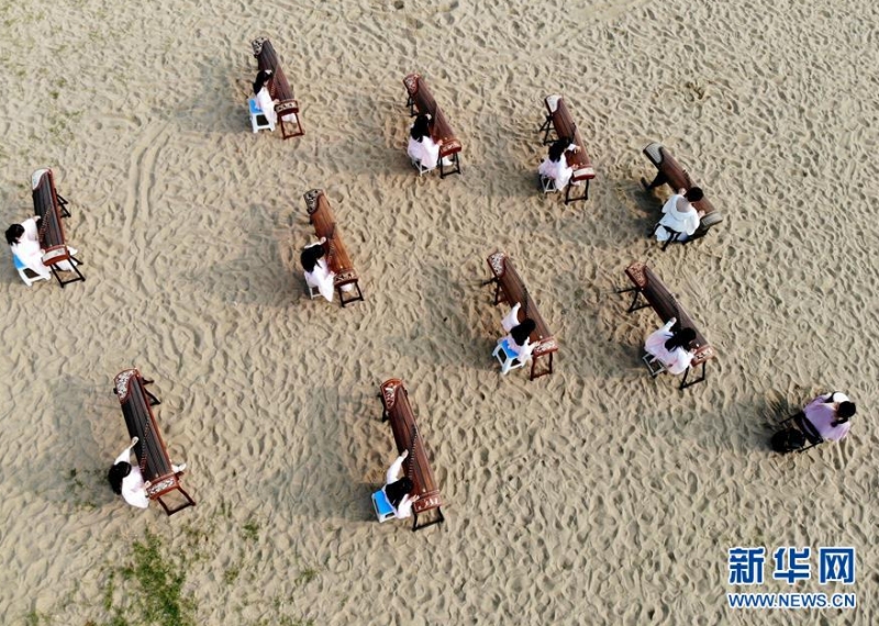 6月26日，在江苏连云港海边的沙滩上，一家琴行的工作人员和小朋友一起演奏古筝（无人机照片）。 当日是端午小长假的第二天，人们外出休闲，亲近自然，欢度假期。 新华社发（王春 摄）