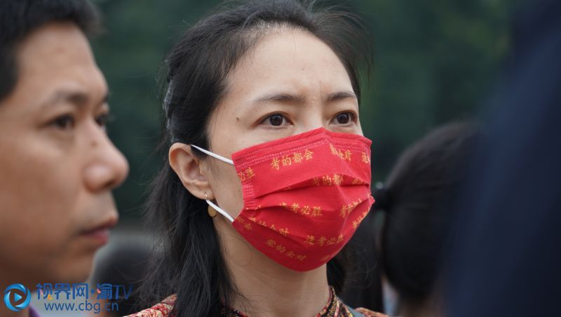 8点10分，一名家长戴着写满祝福语的红色口罩。