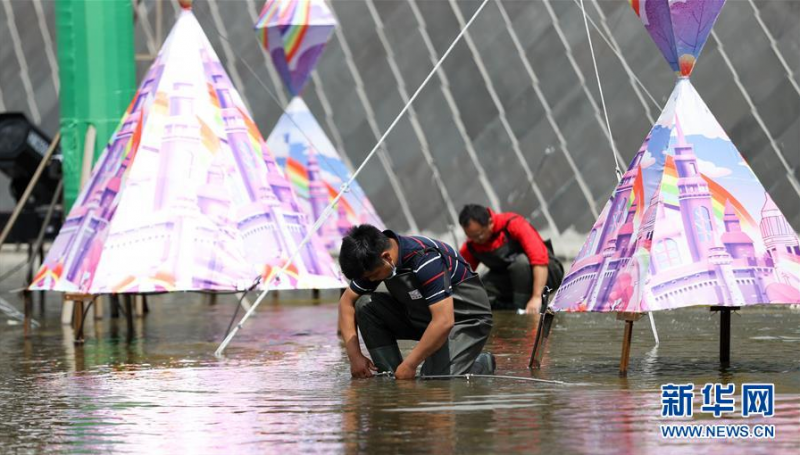6月27日，江成财（前）在长春市长影世纪城内安装彩灯内的技术装置。 新华社发（颜麟蕴摄）