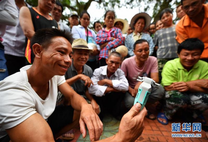 7月15日，琼中县什运乡便文村村民在了解电动割胶刀的构造。 当日，海南琼中黎族苗族自治县什运乡为542名贫困户免费发放电动割胶刀，割胶刀研发单位为贫困户提供使用技能培训。 海南有着丰富的天然橡胶资源，但传统胶刀的割胶技术要求高，农民难以掌握，许多胶林闲置。电动割胶刀使割胶简单易学，帮助村民提高割胶效率，助力脱贫增收。 新华社记者 郭程 摄