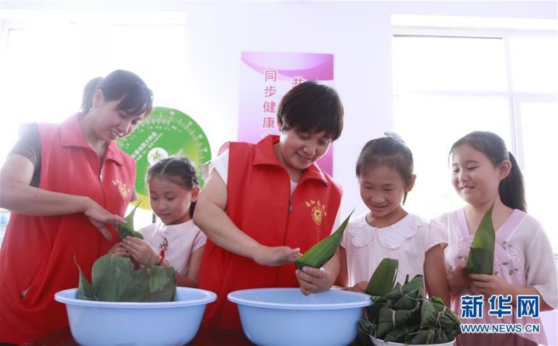 6月24日，河北省邢台市南和区三思乡卫生院的志愿者在南韩村和小朋友一起包粽子。 端午佳节将至，各地群众举行了多种多样的活动迎接这一传统节日。 新华社发（张驰 摄）