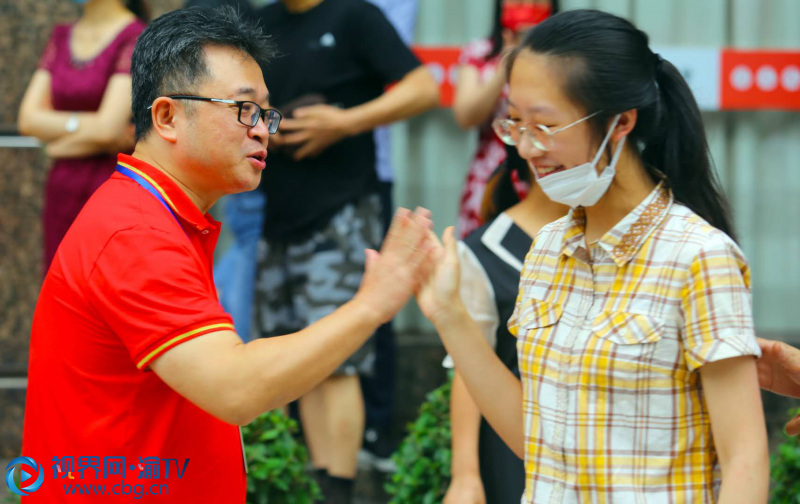 巴蜀中学的送考老师身着红色短袖，与学生击掌为他们加油鼓劲。