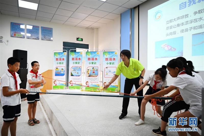 7月10日，在广西柳州市柳北区石碑坪镇中心校，小学生在游泳教练的指导下学习救援技能。 近日，各地学校开展“暑假安全课”主题活动，加强学生们的安全意识。 新华社发（黎寒池 摄）