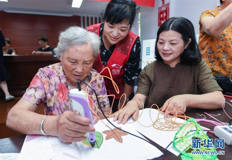6月24日，志愿者指导老人用3D打印笔绘制端午主题图案。 当日，浙江省慈溪市钱海军志愿服务中心的志愿者们来到慈溪市白果树社区，同社区的老人和居民们开展了“‘棕’情端午，与爱同行”迎端午主题活动。志愿者们与老人们一起包粽子、做香囊，迎接端午节。 新华社记者 徐昱 摄