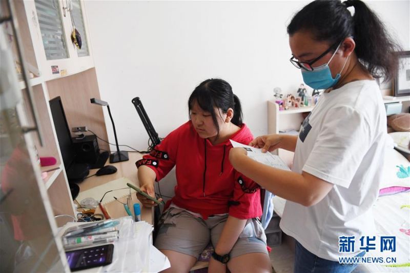 张晶的妈妈在张晶出发前帮她检查准考证（7月7日摄）。新华社记者 鞠焕宗 摄