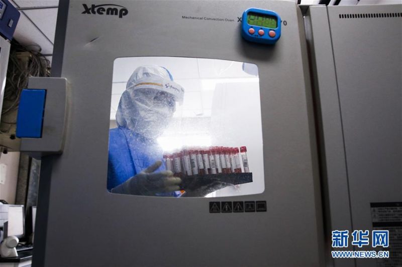 7月3日，中日友好医院检验科新冠核酸检测实验室的检验人员张鑫取出经过灭活的样本。新华社记者 张玉薇 摄