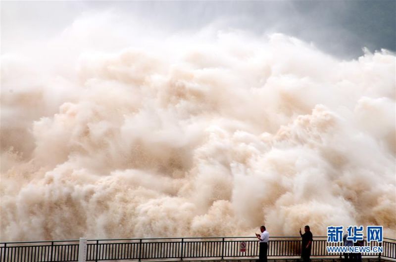 7月4日，游客在小浪底库区观看水库泄洪。 当日，位于河南济源的黄河小浪底水库继续开闸泄洪，清澈的水流和裹挟泥沙的混浊水流分别从明流洞、排沙洞奔腾而出，好似黄白两色的“巨龙”飞腾。 新华社发（苗秋闹 摄）2
