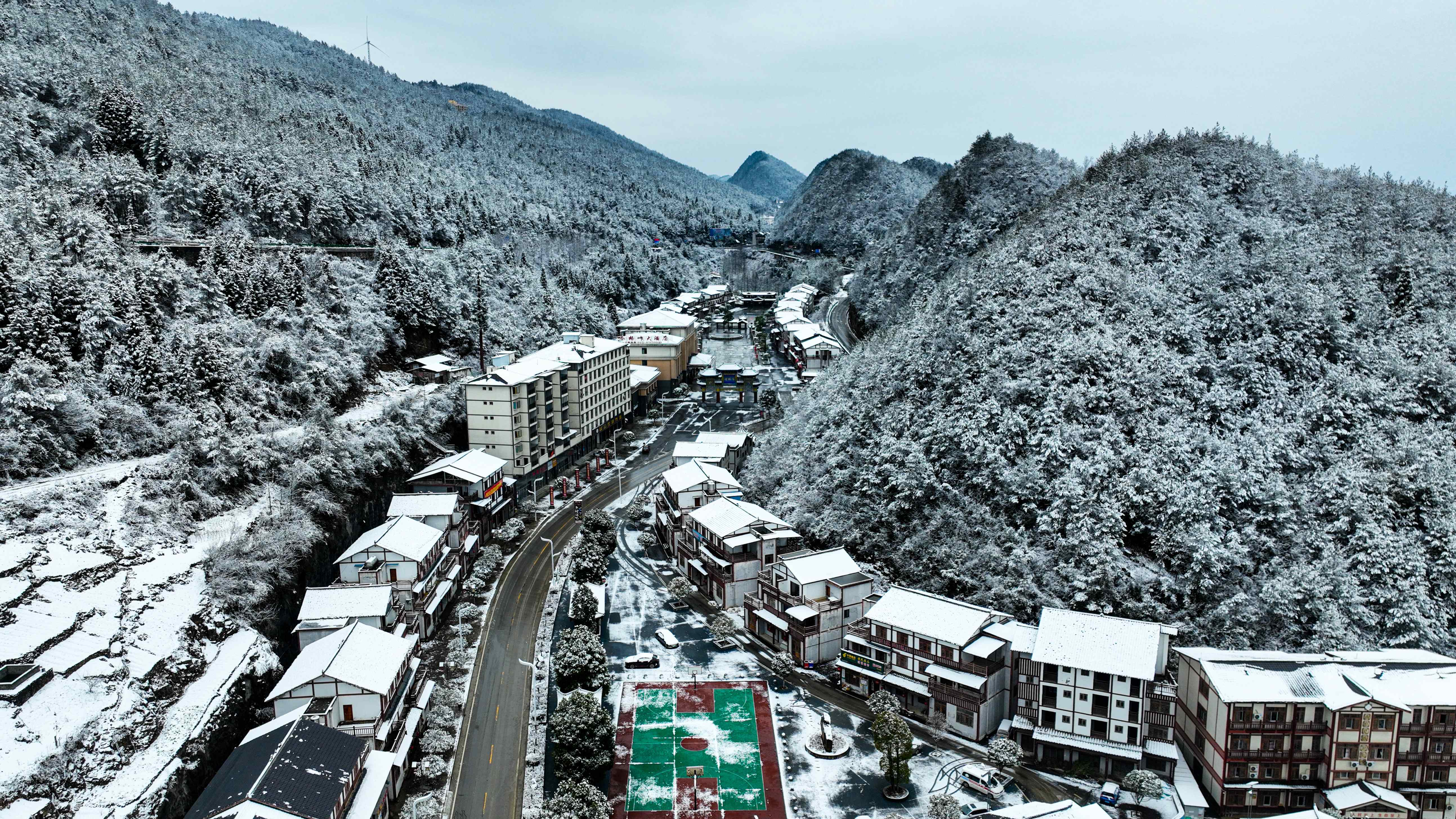 道路两旁的房屋与飘落的雪花交相辉映。（摄影：谭启云）