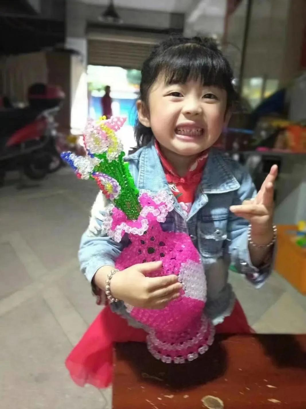 李红梅女儿菲菲抱着母亲制作好的花瓶。（受访者供图）