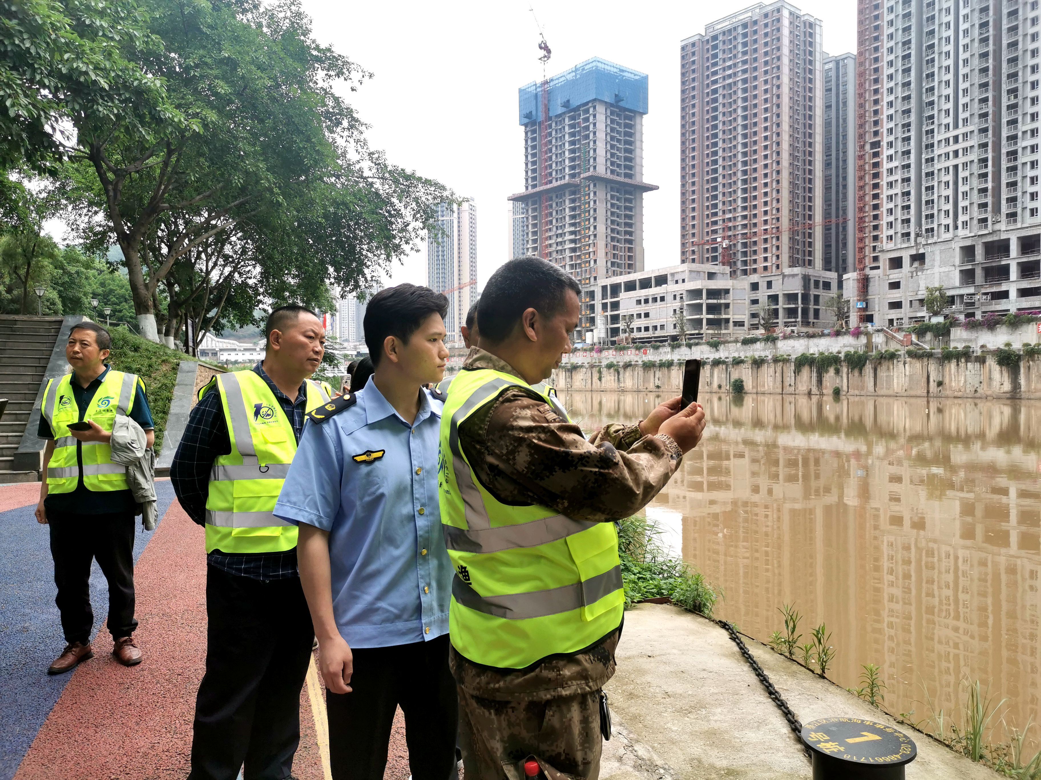 巡河護漁隊隊員用手機拍攝記錄水域情況。（攝影：張靜）