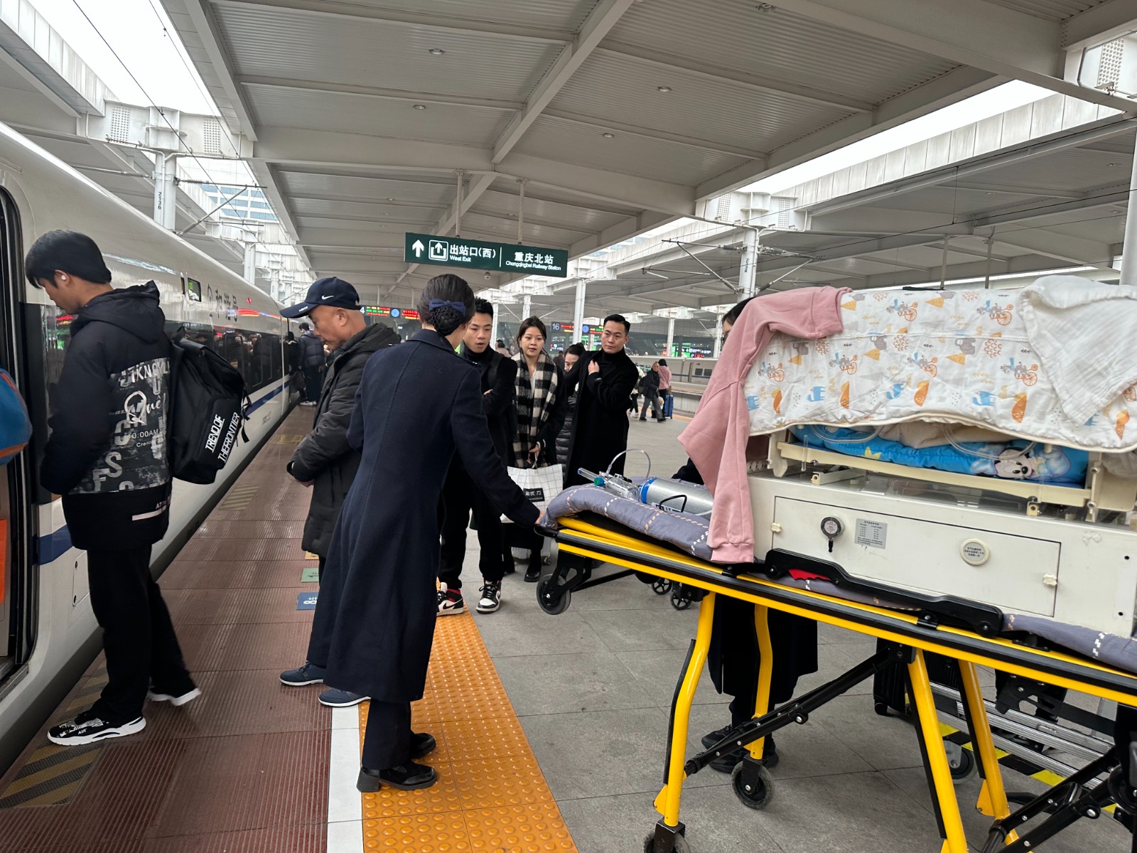 G332次列车到达后，龙梅协助医务人员运送小丞丞上车（李彦熹 摄）.jpg