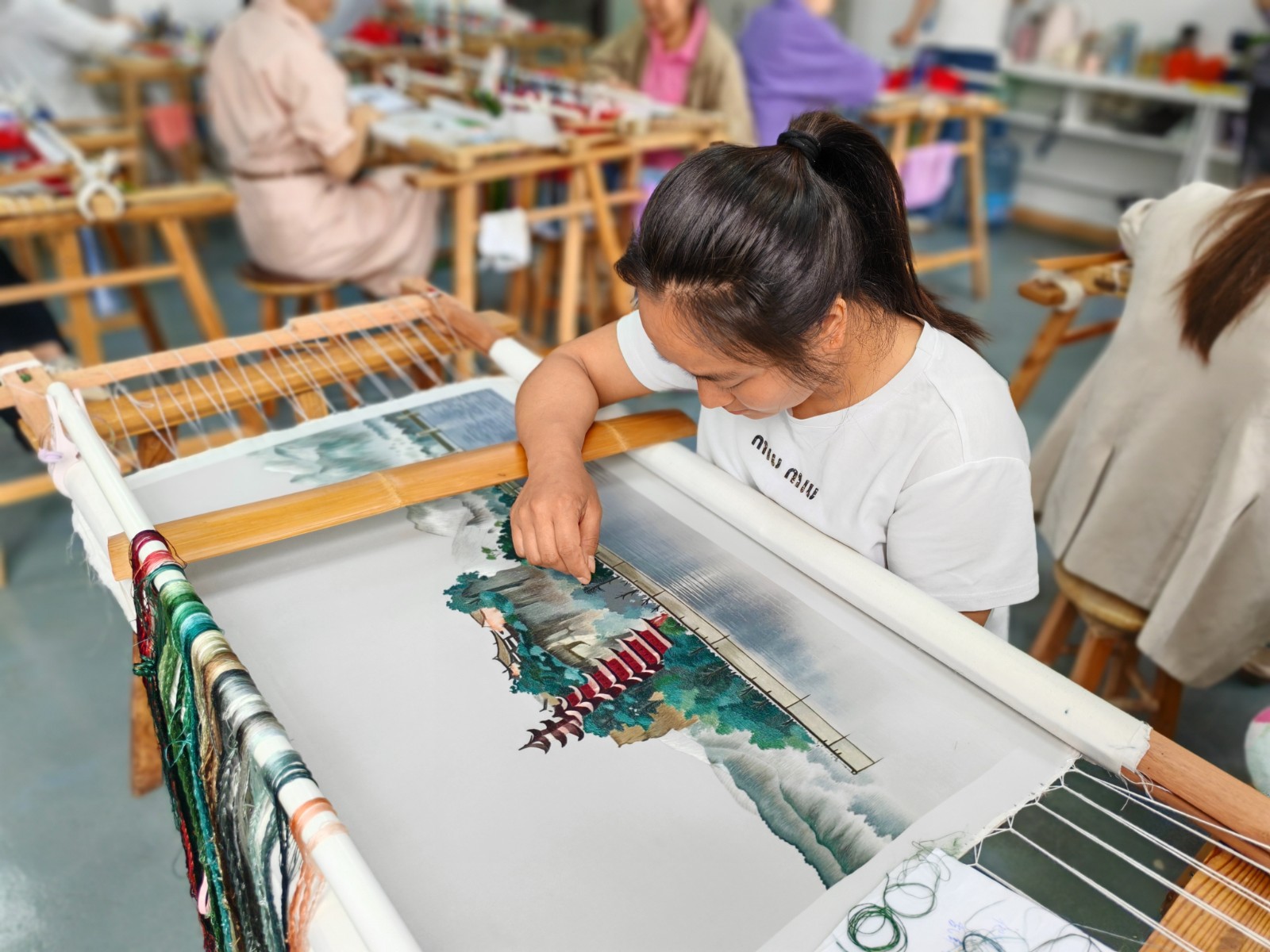 非遗绣娘赵封建正专注刺绣《江上明珠&mdash;石宝寨》。周晶 摄.jpg
